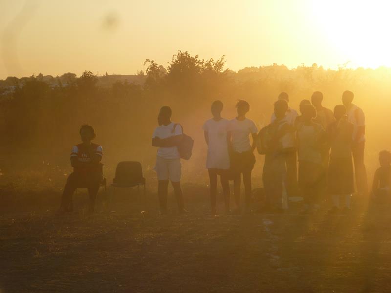 Spectators watch a netball match as the sun goes down